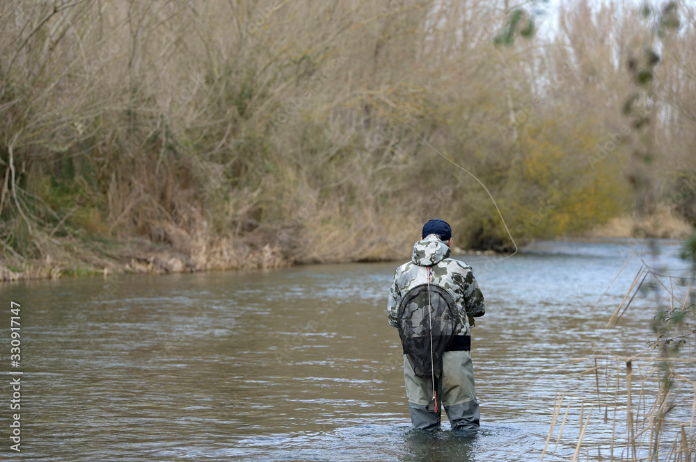 Naklejka premium fly fisherman in river in winter