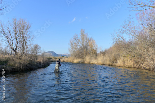 fly fisherman in river in winter