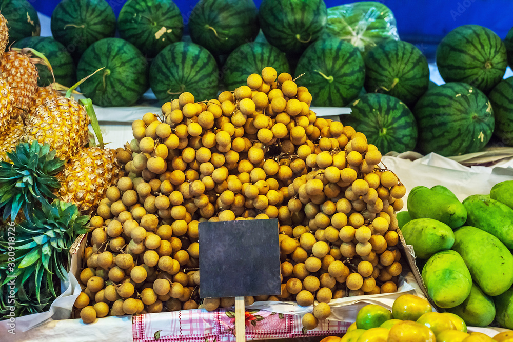 Sweet tropical fruits Dimocarpus longan bunches and pineapples sale at market