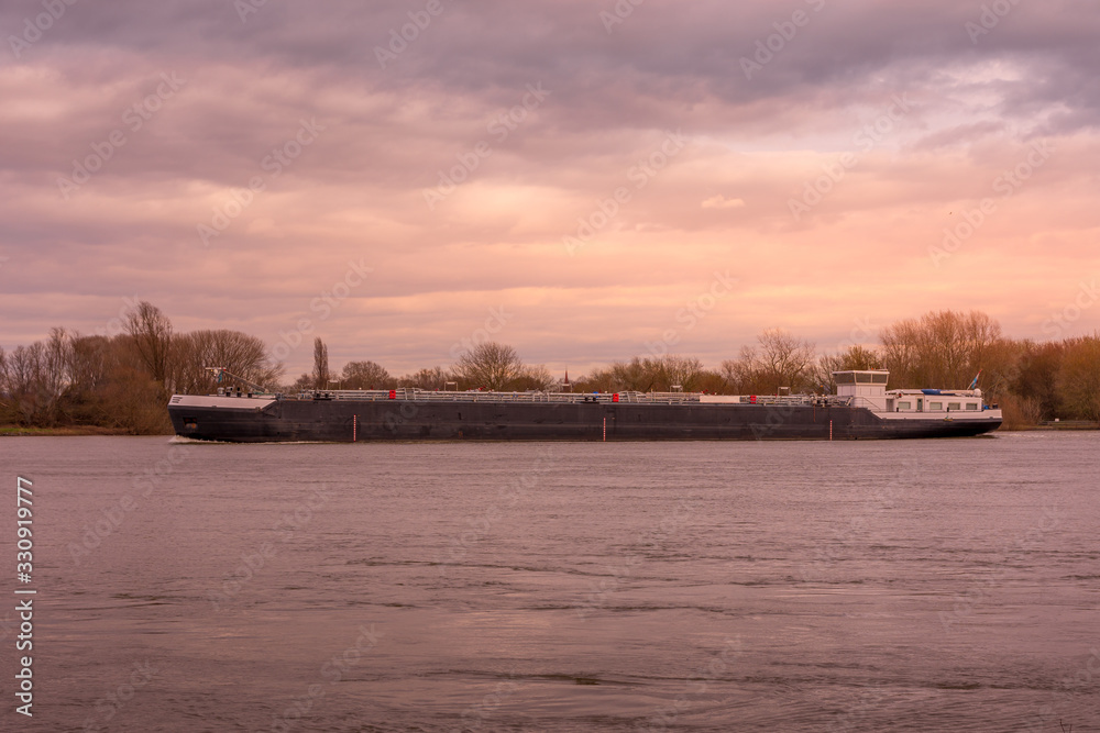 a large cargo ship on a river in the sunset