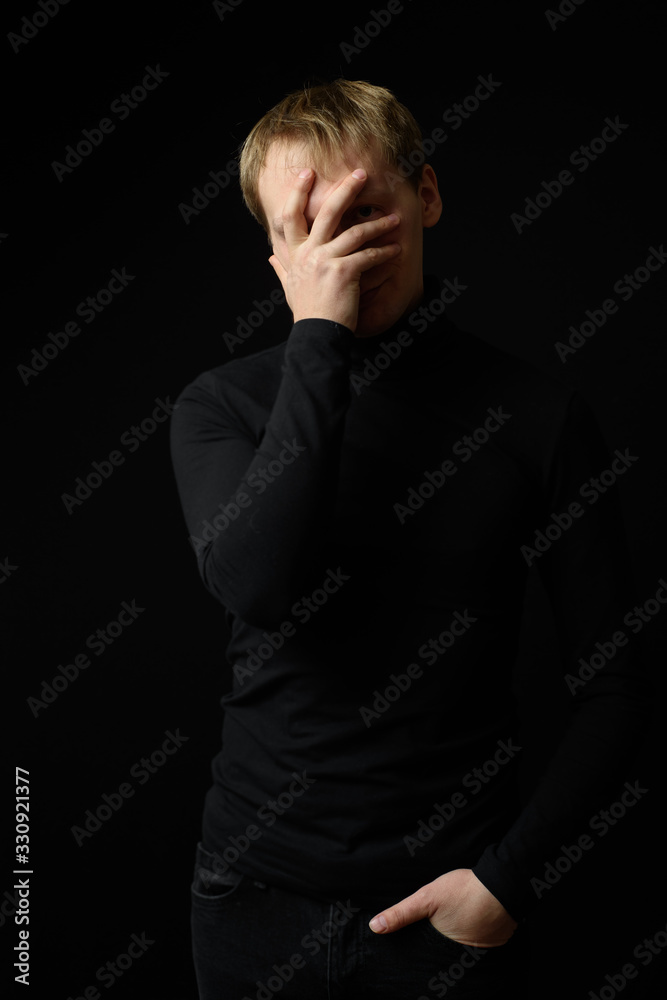 Portrait of determined goodlooking man wearing black shirt, black background.