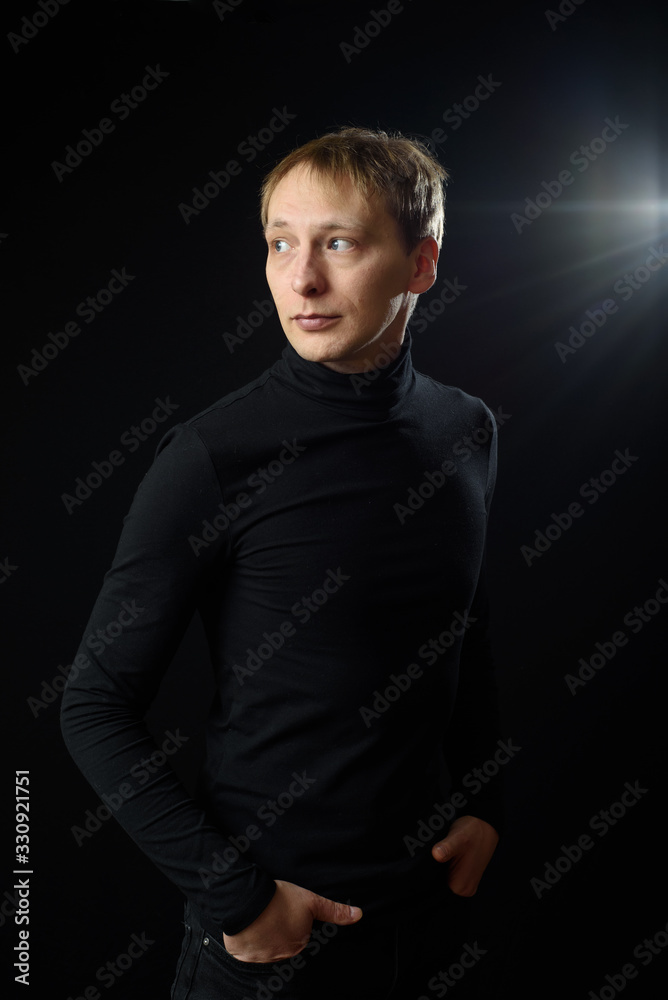 Portrait of determined goodlooking man wearing black shirt, black background.