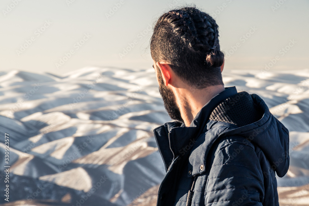 a man standing and looking to amazing landscape in from of him with fascinating mountains covered by snow.