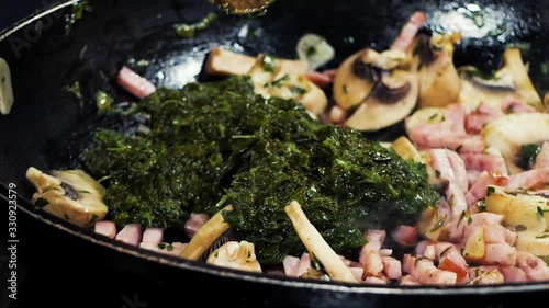 Finely chopped ham, garlic, mushrooms and spinach is fried in hot oil in a pan.