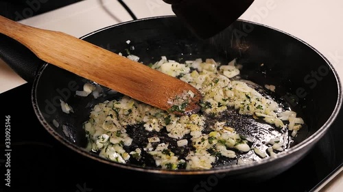 In the fried onions, garlic and herbs, the cook adds pepper from the pepper shaker