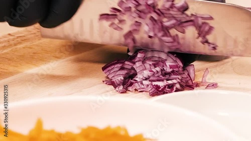 Closeup of slicing red onions with a large metal knife.