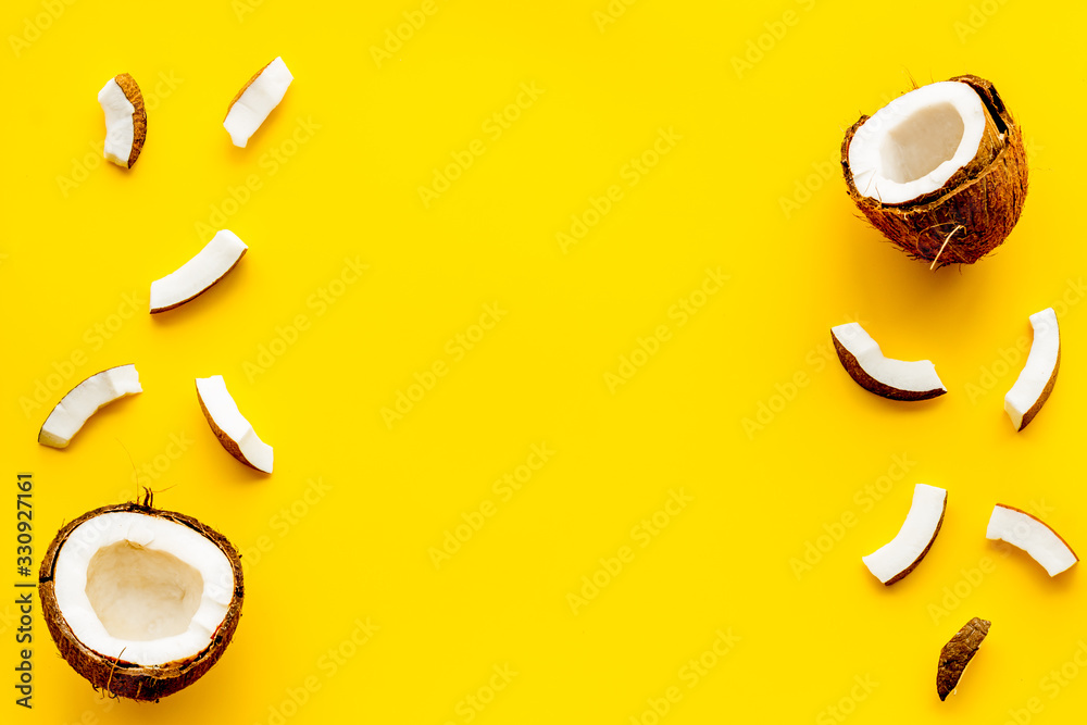Coconuts frame - halfs and scattered pieces - on yellow background top-down copy space