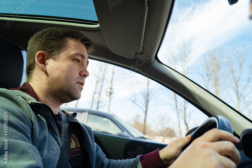 a man in grey sweater behind wheel of car rides