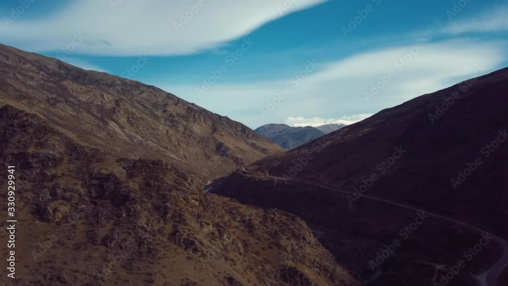 AERIAL: Ascending shot of New Zealand highway travelling between Queenstown mountain range AERIAL: Ascending shot of New Zealand highway travelling between Queenstown mountain range