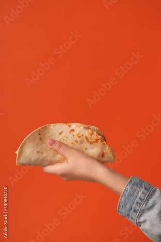 Mexican national food taco or Tatar national food kystyby in hand on an orange background.Food in a tortilla.National food concept photo