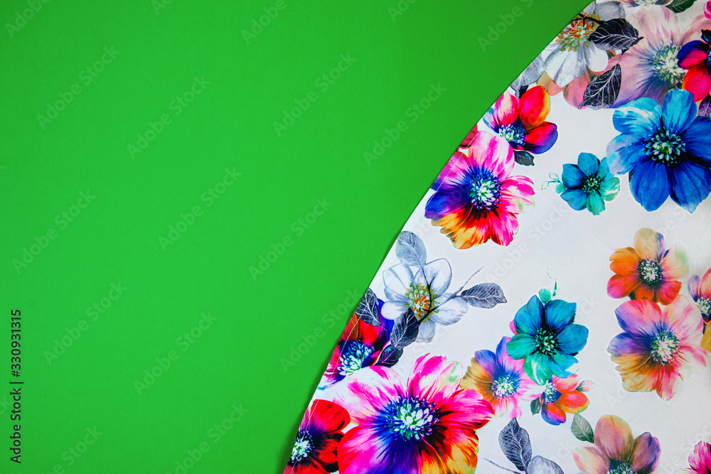 A patch of white fabric with multicolored flowers on a bright green background. Space for text