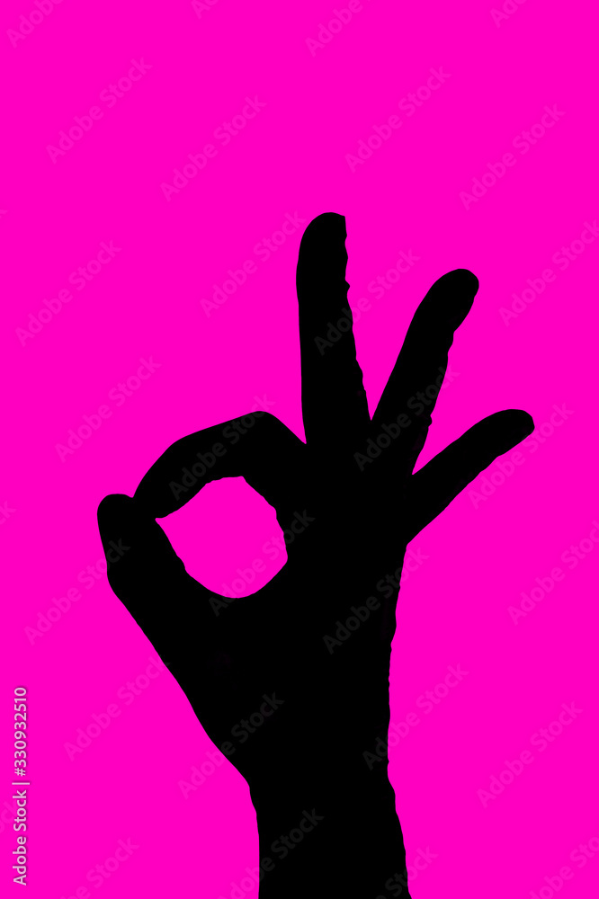 Black silhouette hand OK sign in gloves on fuchsia pink background. Medical positive concept. Fingers symbol Okay Black silhouette hand OK sign in gloves on fuchsia pink background. Medical positive concept. Fingers symbol Okay