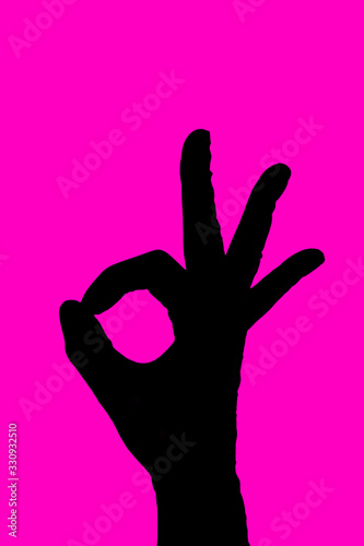 Black silhouette hand OK sign in gloves on fuchsia pink background. Medical positive concept. Fingers symbol Okay