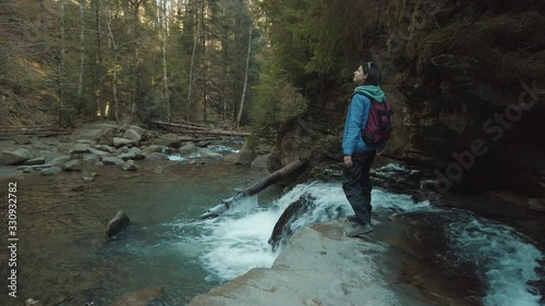Female backpacker walking on rocks at the stream. Girl traveler enjoying of outdoor traveling. Recreating of life and self isolating.