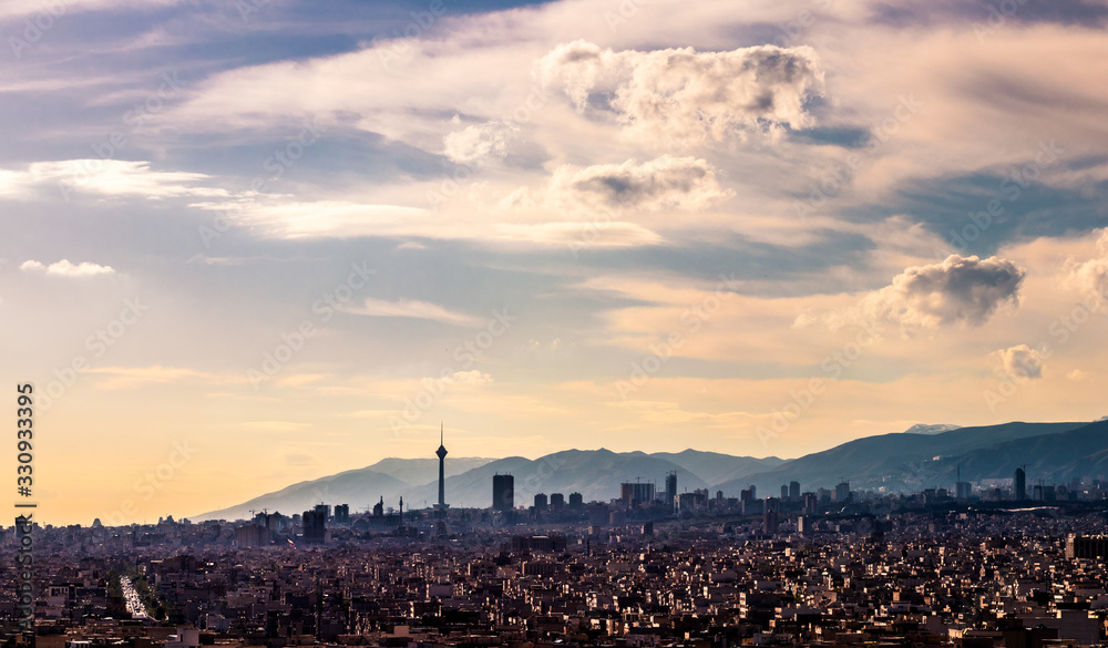 Tehran skyline in a beautiful cloudy day with golden hour light Tehran-Iran cityscape with Milad tower in photo and white clouds and lovely blue sky