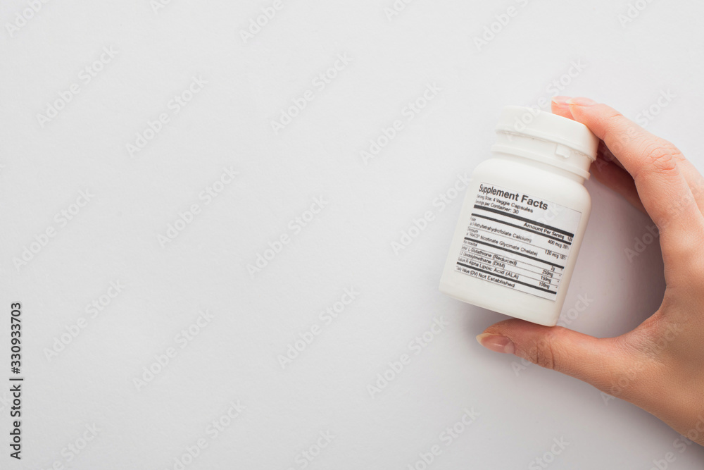 Cropped view of woman holding container with dietary supplements on white Cropped view of woman holding container with dietary supplements on white