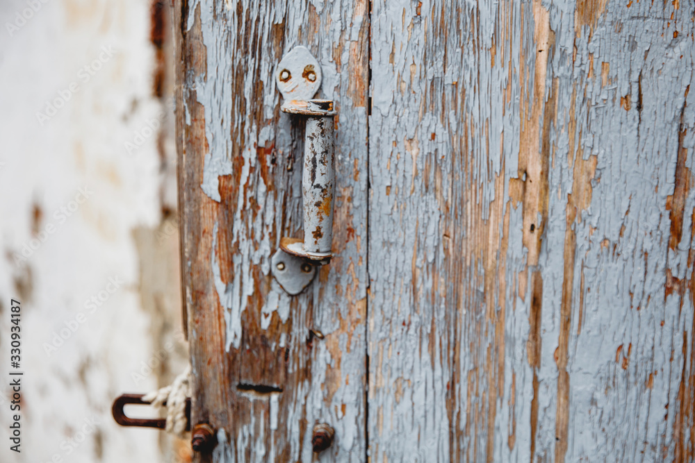Old wooden door with remnants of old paint. A handle is bolted to the door. Old wooden door with remnants of old paint. A handle is bolted to the door.