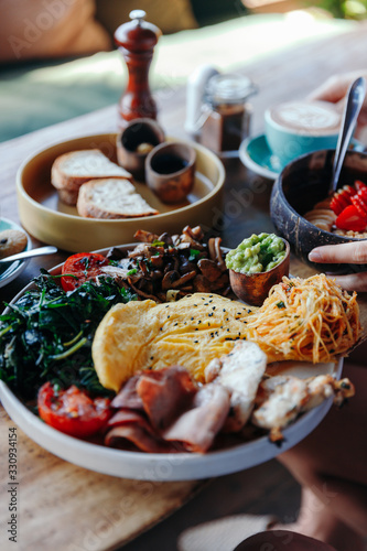 Morning breakfast on a table, waffles with cream, berries, coffee, cappuccino, bowl, omlet with vegetables, bread with butter, avocado cream, vegan food, healthy food, meal.
