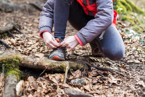 Portrait of girl on hiking forest trip tying shoe laces.