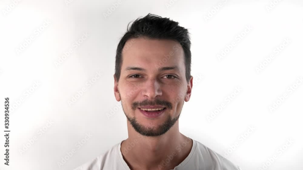 Caucasian brunette short hair man with a beard in the studio on a white background in a white T-shirt smiles strait to the camera, close-up Caucasian brunette short hair man with a beard in the studio on a white background in a white T-shirt smiles strait to the camera, close-up