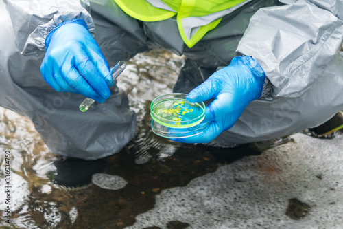 the specialist’s hands in protective clothing hold a plant sample from the bottom of the river and does an express analysis for the presence of harmful substances in the environment © kurgu128