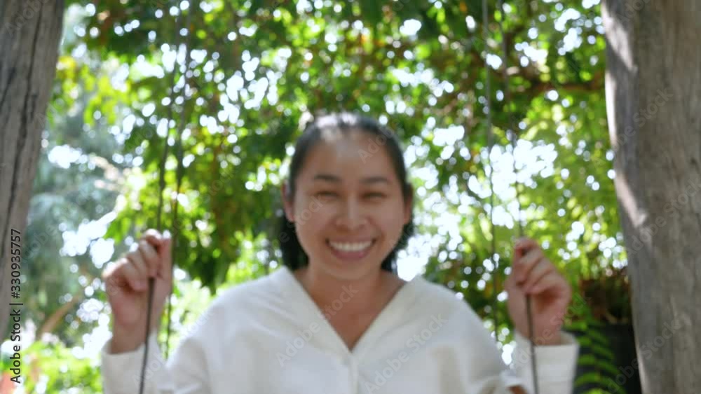 Happy young woman laughing as she plays on a swing in the park. Concept of lifestyle in summer vacation. Happy young woman laughing as she plays on a swing in the park. Concept of lifestyle in summer vacation.