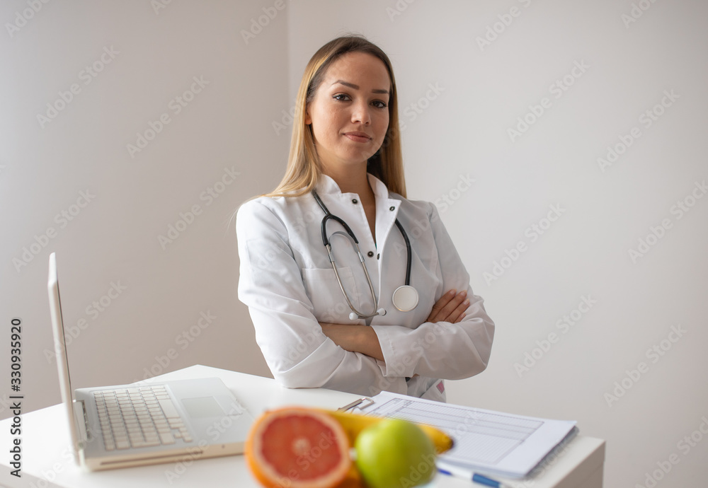 Female nutritionist with fruits working at her desk. Smiling nutritionist in her office, she is showing healthy vegetables and fruits, healthcare and diet concept. Female nutritionist with fruits working at her desk. Smiling nutritionist in her office, she is showing healthy vegetables and fruits, healthcare and diet concept.