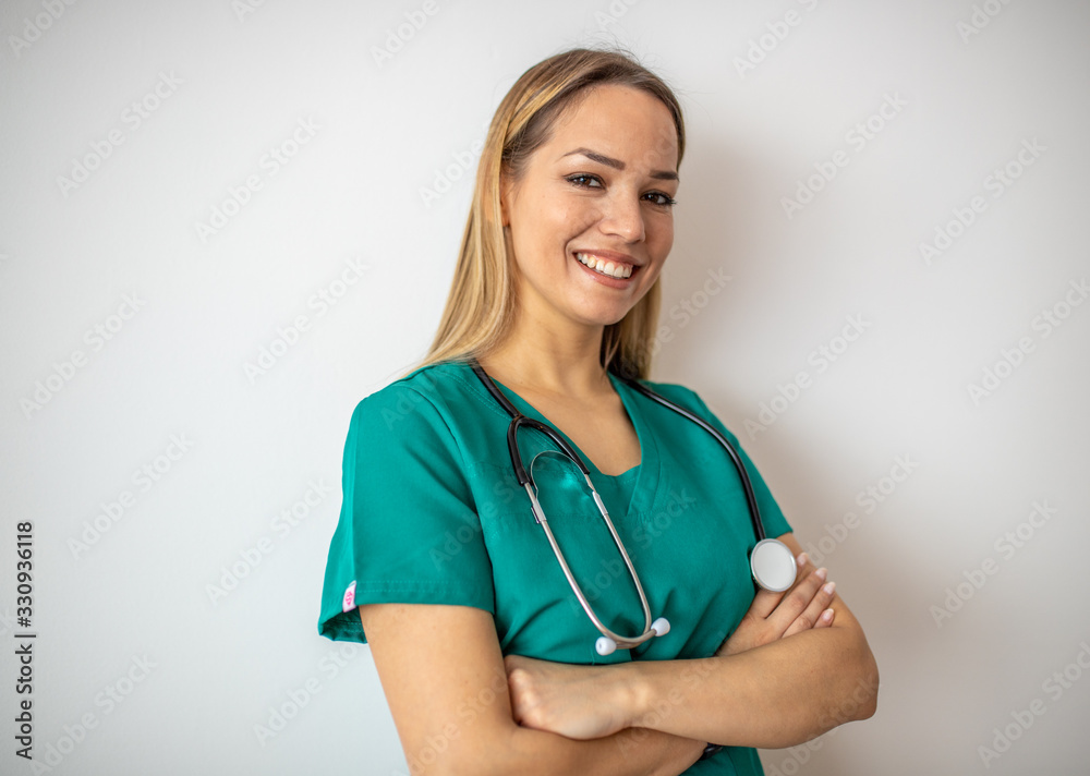 Female nurse standing arms crossed. Confident young woman doctor. Female nurse, young pretty woman in green clothes smiling Female nurse standing arms crossed. Confident young woman doctor. Female nurse, young pretty woman in green clothes smiling