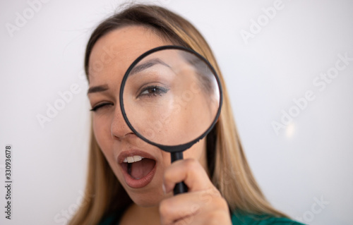 Young attractive woman looking through magnifying glass