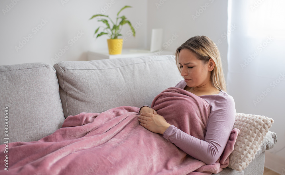 Woman having stomach issues / problems while lying on the couch Woman having stomach issues / problems while lying on the couch