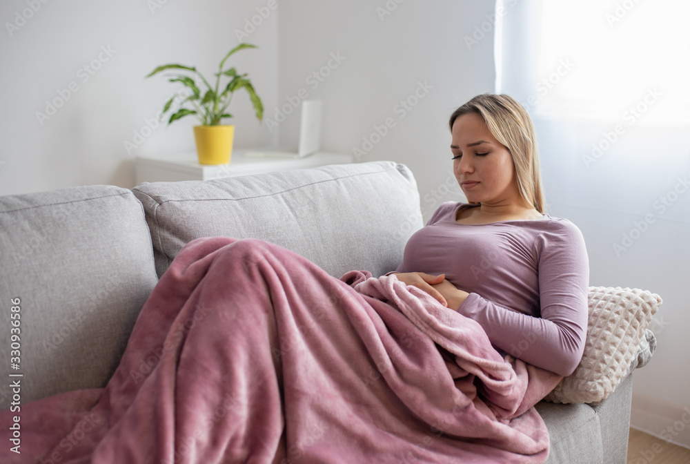 Woman having stomach issues / problems while lying on the couch
