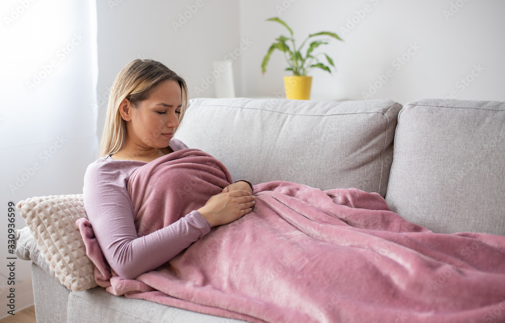 Woman having stomach issues / problems while lying on the couch Woman having stomach issues / problems while lying on the couch
