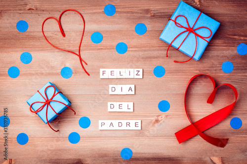 Obraz na plátně Feliz dia del padre words made of wooden blocks with blue gift boxes and red hearts on wooden background