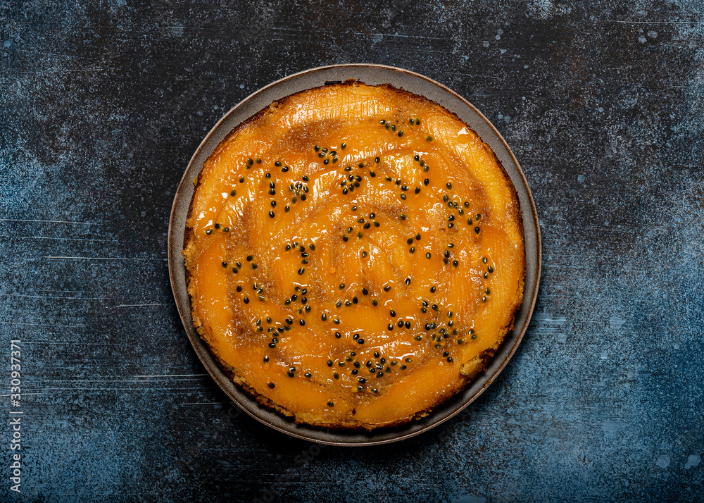 Homemade mango upside down cake with and passion fruit on a dark rustic background. Delicious vegetarian sweet food concept. Horizontal view from above. Copy space. Homemade mango upside down cake with and passion fruit on a dark rustic background. Delicious vegetarian sweet food concept. Horizontal view from above. Copy space.