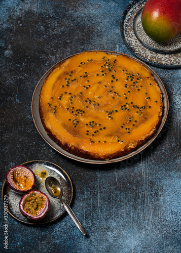 Traditional fresh baked mango upside down cake with passion fruit on a dark rustic background. Delicious homemade sweet food concept. Selective focus. Copy space.