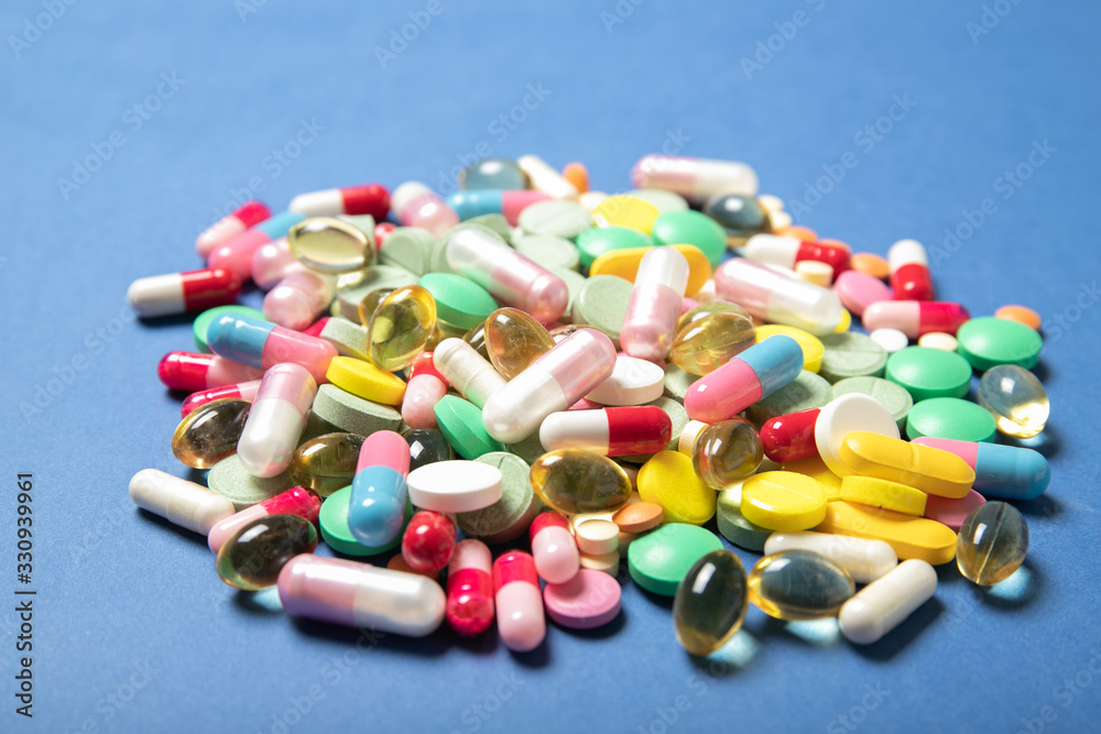 Pills and capsules on a blue background, place for text.