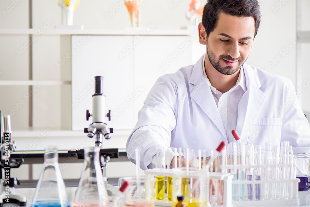 Attractive happiness scientist man lab technician assistant analyzing sample in test tube at laboratory. Medical, pharmaceutical and scientific research and development concept. Attractive happiness scientist man lab technician assistant analyzing sample in test tube at laboratory. Medical, pharmaceutical and scientific research and development concept.