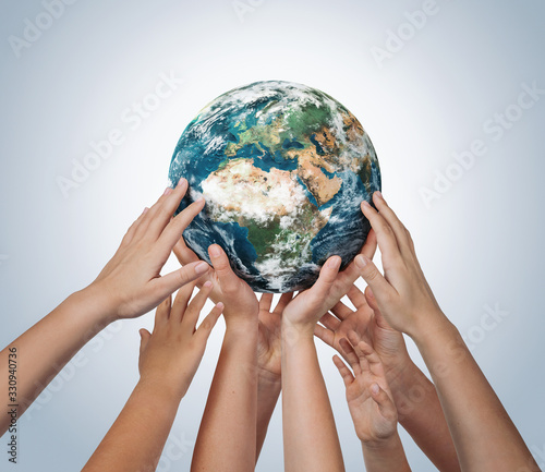 Fototapeta Naklejka Na Ścianę i Meble -  Many children hands holding planet earth isolated on blue background with copy space