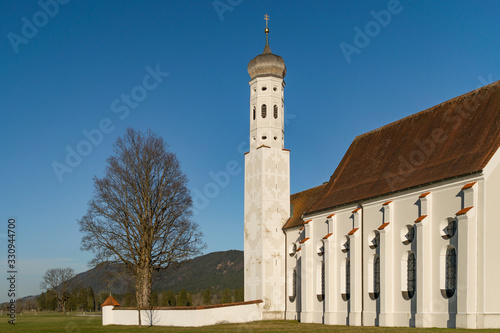 Kirche Sankt Colomar im Allgäu. Die Kirche steht auf einem Feld bei Schwangau und Füssen und ist umgeben von den Alpen.