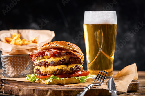 Set of hamburger beer and french fries. A standard set of drinks and food in the pub, beer and snacks. Dark background, fast food. Traditional american food. photo