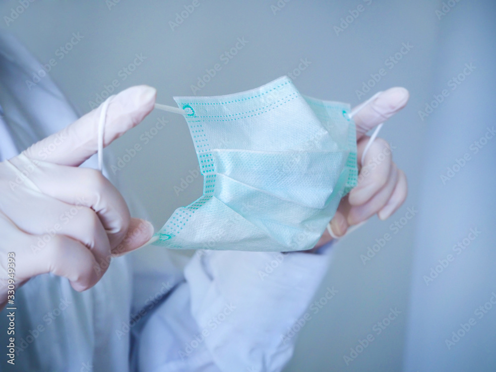 Fototapeta premium Pandemic Coronavirus. Close up of hands holding a face mask against virus.