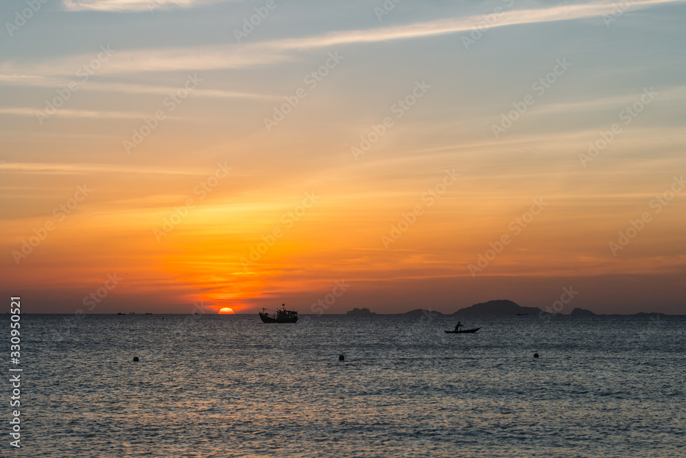 Colorful dawn, sunset on a calm sea. Silhouette of a fishing boat on the horizon.  Beautiful sea background, landscape. Fiery colors.