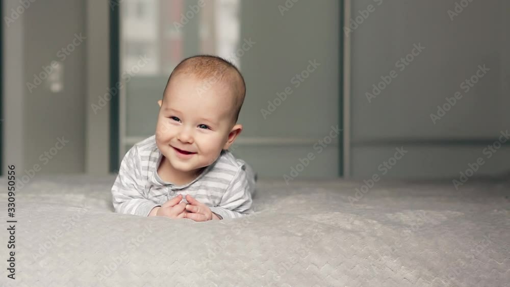 Cute baby lies on bed looking in the camera and smiling Cute baby lies on bed looking in the camera and smiling