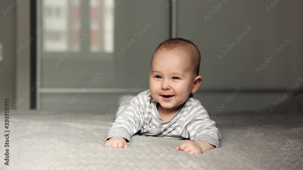 Cute baby lies on bed looking in the camera and smiling Cute baby lies on bed looking in the camera and smiling