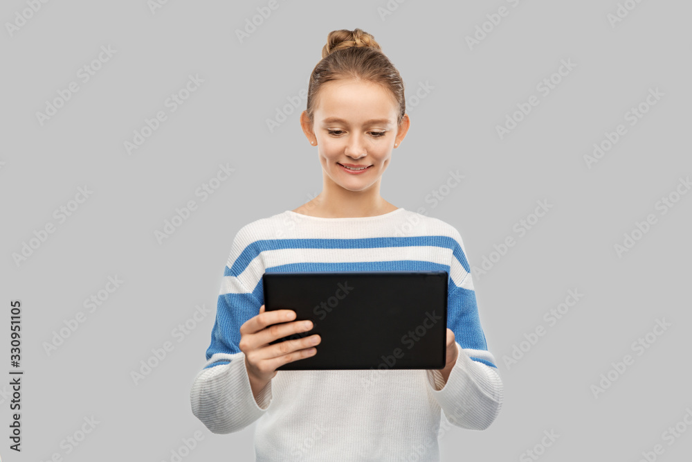 technology, communication and people concept - happy smiling teenage girl in pullover using tablet pc computer over grey background technology, communication and people concept - happy smiling teenage girl in pullover using tablet pc computer over grey background