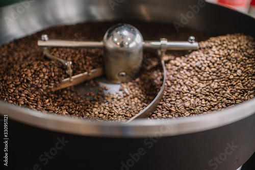 Freshly light roasted arabica coffee beans cooling in a roasters drum.