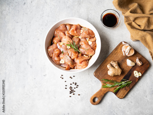 Raw diet marinated turkey meat with garlic, ginger and teriyaki sauce in a white bowl. Marinating meat for cooking barbecue. Top view photo