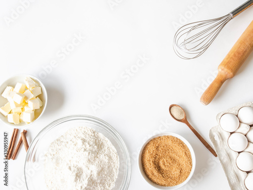 Billede på lærred Frame of various baking ingredients - flour, eggs, sugar, butter, dry yeast, nuts and kitchen utensils on white background