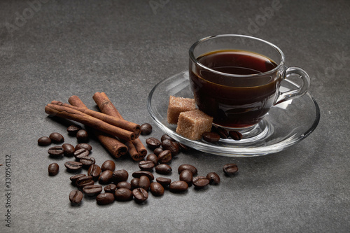 glass Cup of coffee beans with cinnamon and sugar on a dark wooden background