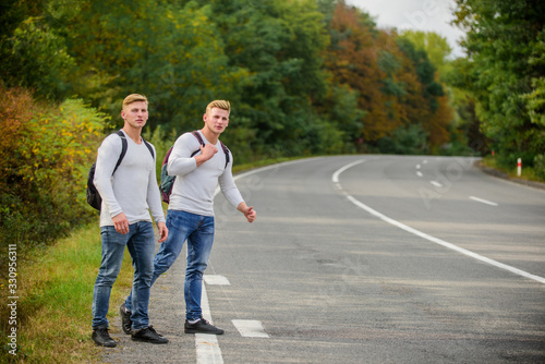 Reason people pick up hitchhikers. Missed their bus. Need help. Cheap transport. Transport problem. Travel and transport concept. Twins men at edge of road nature background. Try to stop some car